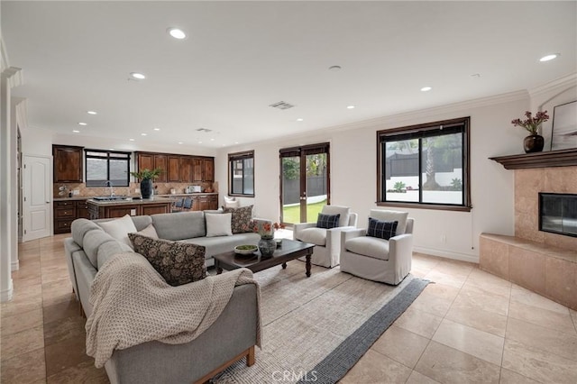 tiled living room with ornamental molding, french doors, and a tiled fireplace