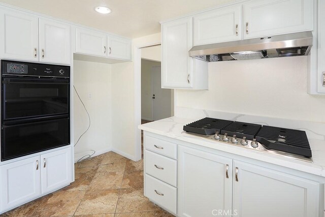 kitchen with white cabinetry, black double oven, light stone counters, and stainless steel gas cooktop