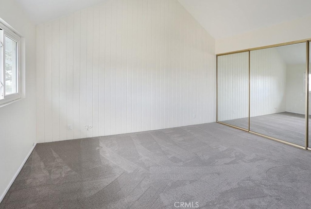 unfurnished bedroom featuring carpet flooring, a closet, and lofted ceiling