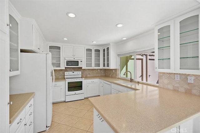 kitchen featuring white appliances, white cabinets, sink, light tile patterned floors, and kitchen peninsula