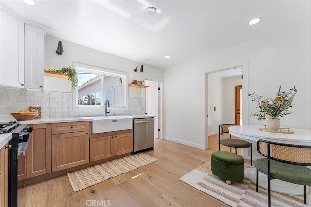 kitchen with white cabinets, sink, backsplash, appliances with stainless steel finishes, and light hardwood / wood-style floors