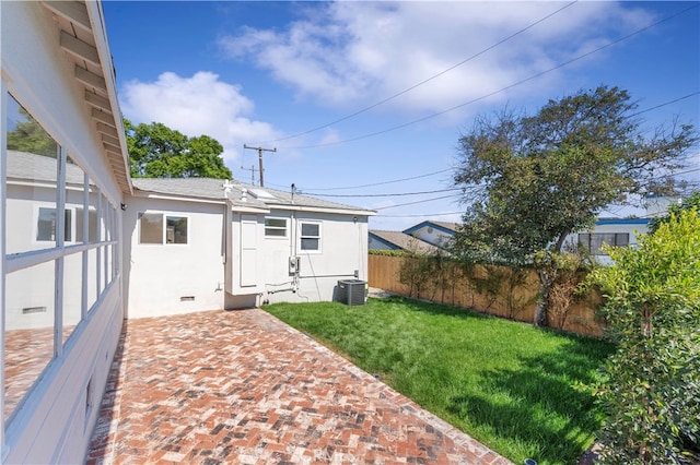 rear view of property with cooling unit, a yard, and a patio area