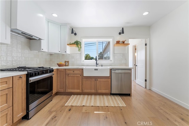 kitchen with white cabinets, appliances with stainless steel finishes, light wood-type flooring, and premium range hood