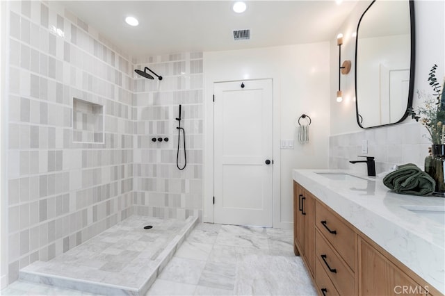 bathroom with a tile shower, vanity, and tasteful backsplash