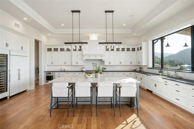 kitchen featuring paneled fridge, a tray ceiling, visible vents, and oven