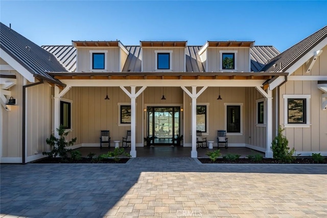 rear view of house with a porch, board and batten siding, metal roof, and a standing seam roof