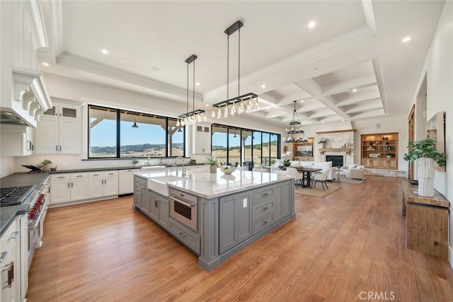 kitchen with light wood-type flooring, gray cabinetry, white cabinetry, coffered ceiling, and dark stone counters