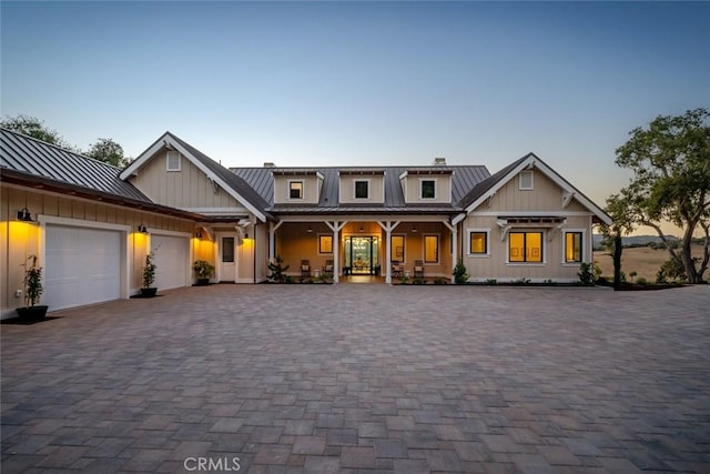 view of front of house with a standing seam roof, an attached garage, decorative driveway, board and batten siding, and metal roof