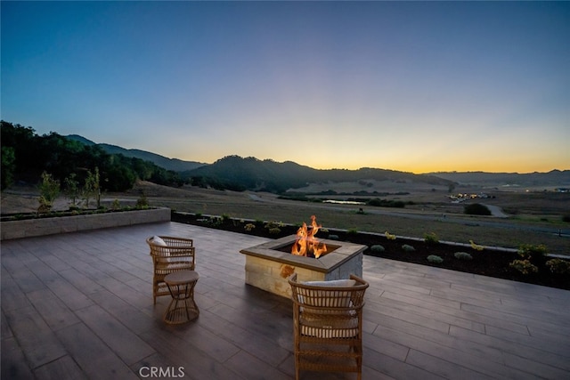 patio terrace at dusk featuring a mountain view and a fire pit