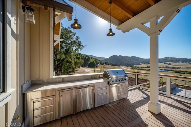 wooden terrace featuring a grill, a mountain view, and area for grilling