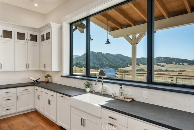 kitchen featuring a mountain view, light hardwood / wood-style floors, wood ceiling, and white cabinets