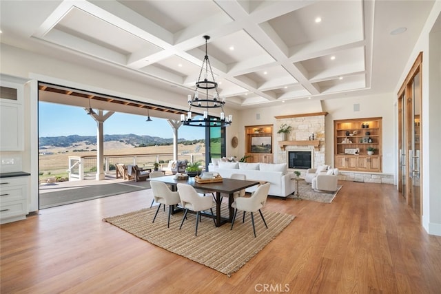 dining area with a mountain view, beamed ceiling, coffered ceiling, a fireplace, and hardwood / wood-style floors