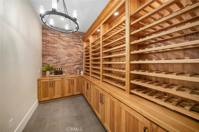 wine area featuring an inviting chandelier, dark hardwood / wood-style flooring, and brick wall