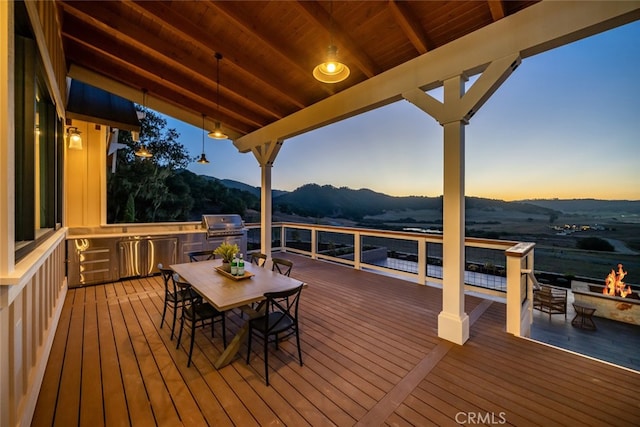 deck at dusk featuring a mountain view and a grill