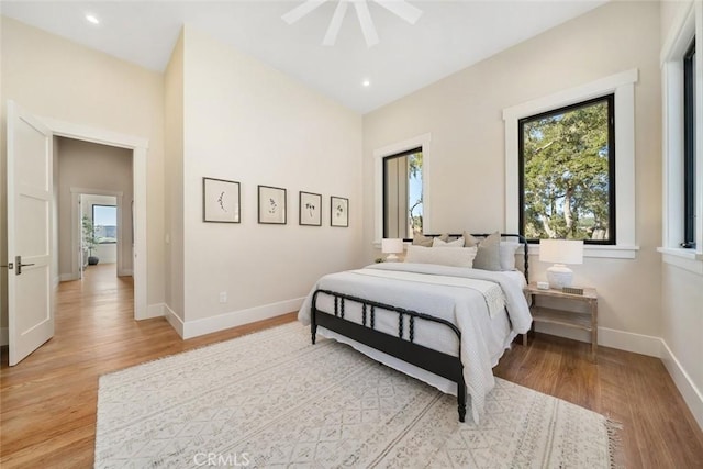 bedroom with light wood-type flooring, multiple windows, and baseboards