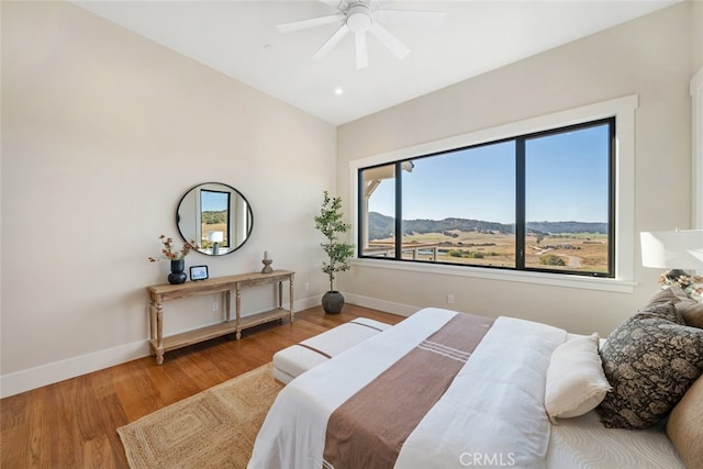 bedroom with lofted ceiling, a mountain view, ceiling fan, and hardwood / wood-style floors