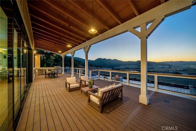 deck at dusk featuring a mountain view, outdoor dining space, and outdoor lounge area