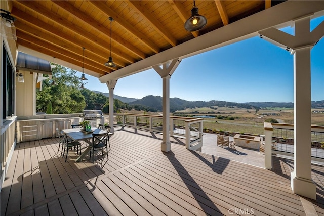 wooden deck with ceiling fan, a mountain view, a rural view, and a grill