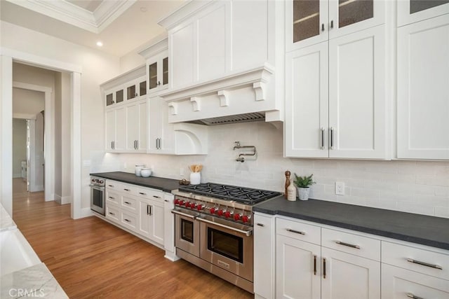 kitchen with light wood finished floors, tasteful backsplash, ornamental molding, white cabinets, and stainless steel appliances