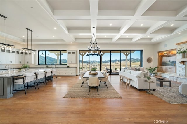 dining area featuring light wood-type flooring, a healthy amount of sunlight, and beamed ceiling