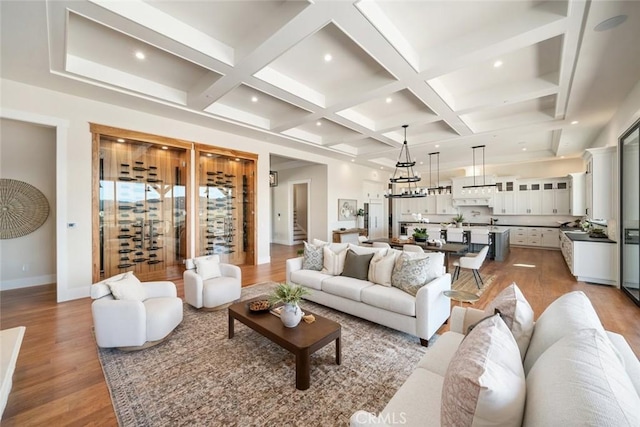 living room with beam ceiling, stairway, coffered ceiling, and light wood-style floors