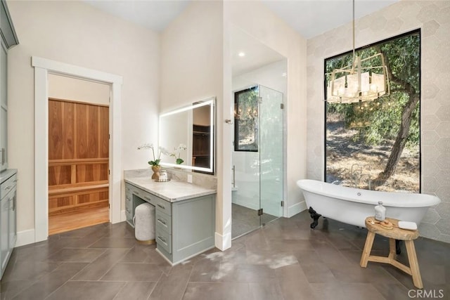 full bath with a freestanding bath, a stall shower, tile patterned floors, a notable chandelier, and vanity