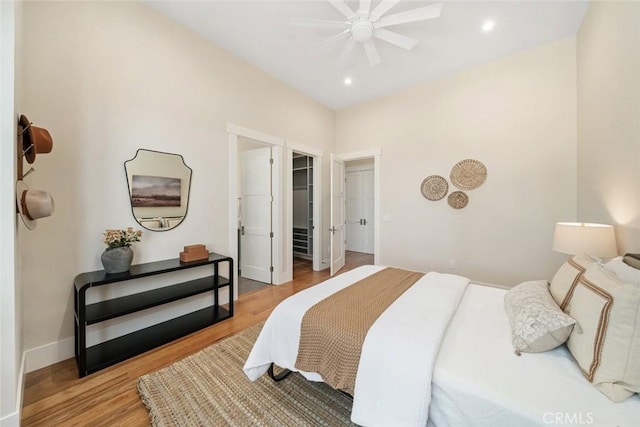 bedroom with a walk in closet, light wood-style flooring, recessed lighting, baseboards, and ceiling fan