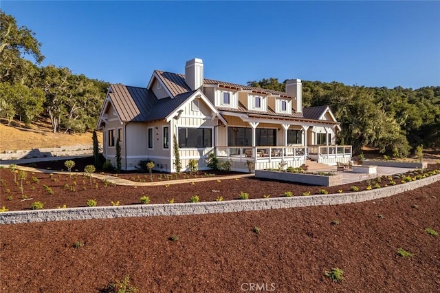 view of front of house with metal roof, a chimney, and a standing seam roof