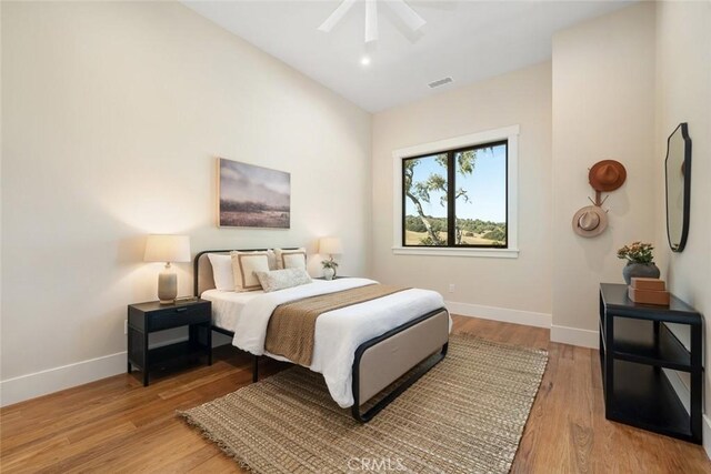 bedroom featuring light wood-type flooring, visible vents, baseboards, and a ceiling fan