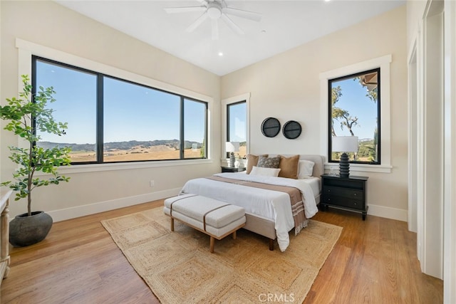 bedroom featuring multiple windows, light hardwood / wood-style floors, and ceiling fan