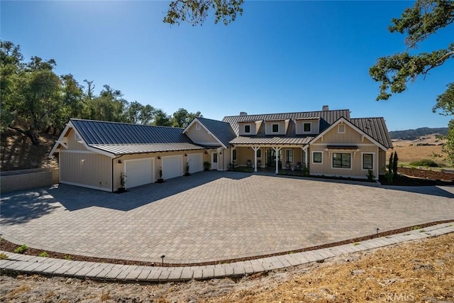 view of front facade with a standing seam roof, a garage, decorative driveway, board and batten siding, and metal roof