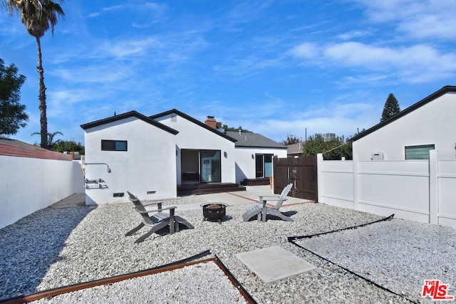 rear view of property with a patio and a fire pit