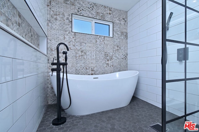 bathroom with a bathtub, tile patterned floors, and tile walls