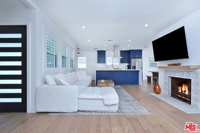 living room with a tiled fireplace and light hardwood / wood-style flooring