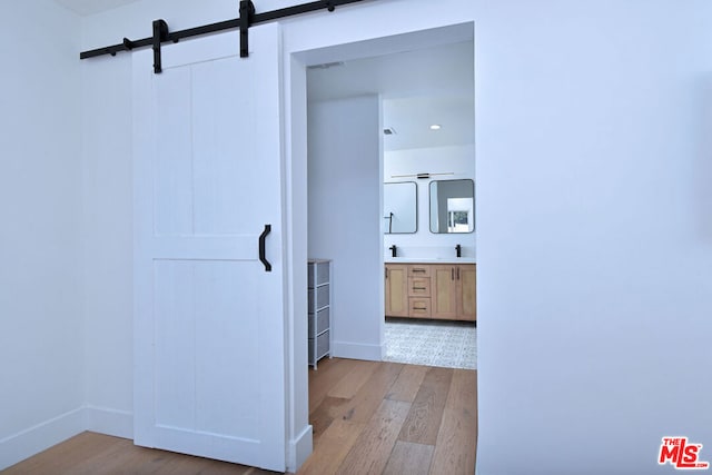 hallway featuring a barn door, light hardwood / wood-style flooring, and sink