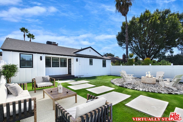 rear view of house with a lawn, a patio area, and an outdoor living space with a fire pit