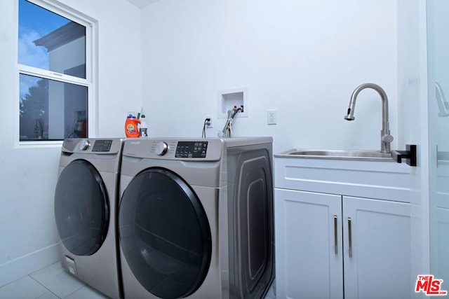 laundry area with cabinets, light tile patterned floors, sink, and washing machine and clothes dryer