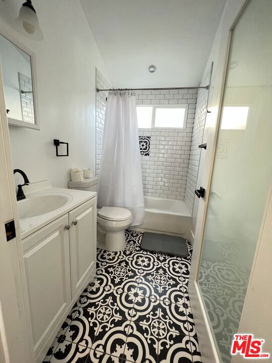 full bathroom with tile patterned flooring, vanity, toilet, and shower / bath combo with shower curtain