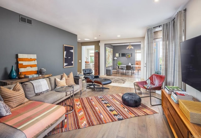 living room with light wood-type flooring and an inviting chandelier