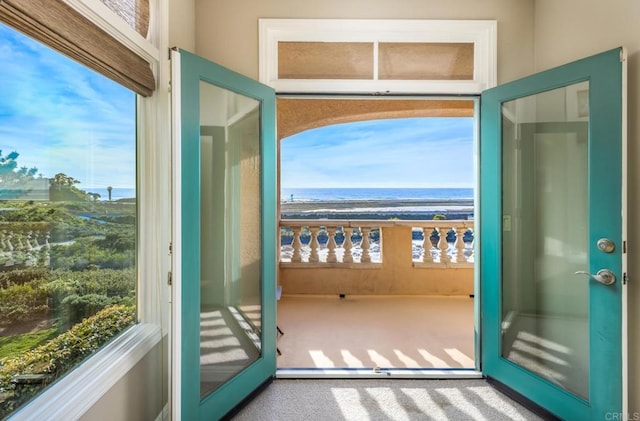 doorway to outside featuring plenty of natural light, a water view, carpet floors, and a view of the beach