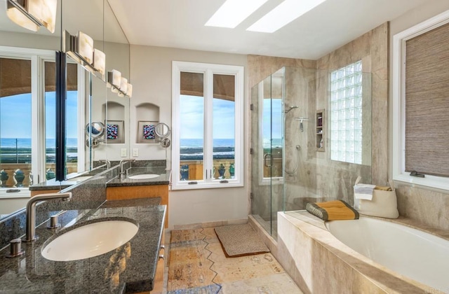 bathroom featuring a skylight, vanity, a water view, and independent shower and bath