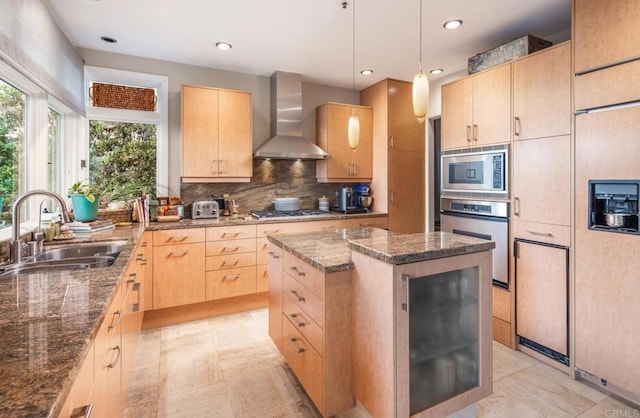 kitchen featuring a center island, wall chimney exhaust hood, light brown cabinets, sink, and appliances with stainless steel finishes