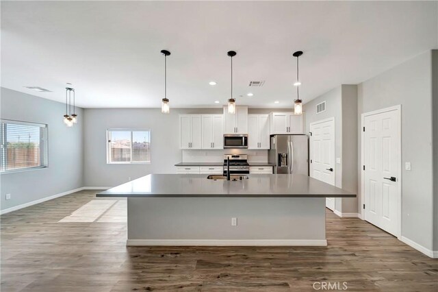 kitchen featuring a center island with sink, appliances with stainless steel finishes, dark hardwood / wood-style floors, and white cabinetry