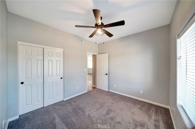 unfurnished bedroom featuring dark colored carpet, ceiling fan, and a closet