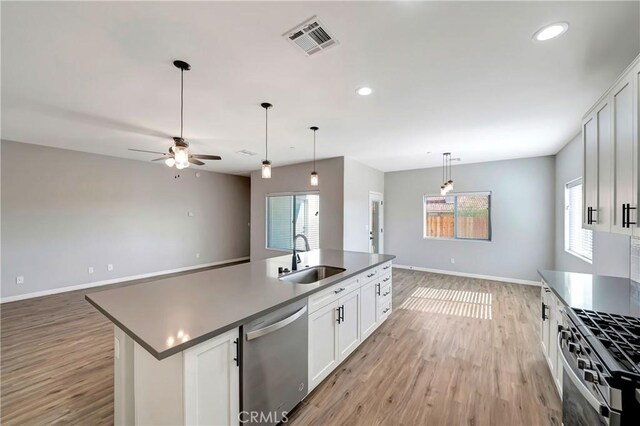 kitchen with a kitchen island with sink, sink, stainless steel appliances, and white cabinets