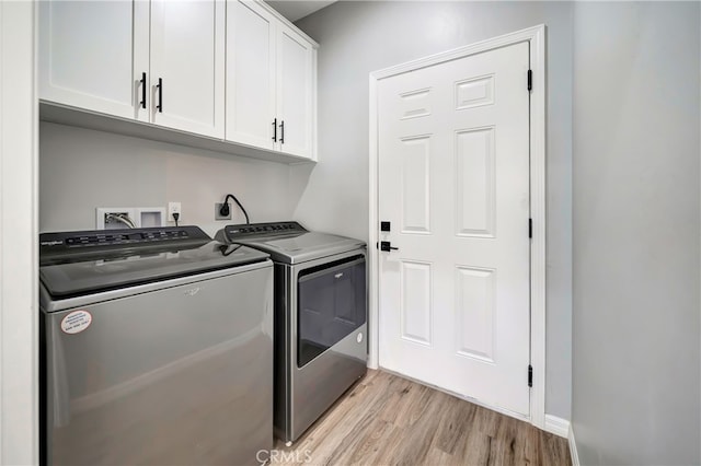 washroom with cabinets, light hardwood / wood-style floors, and washer and clothes dryer