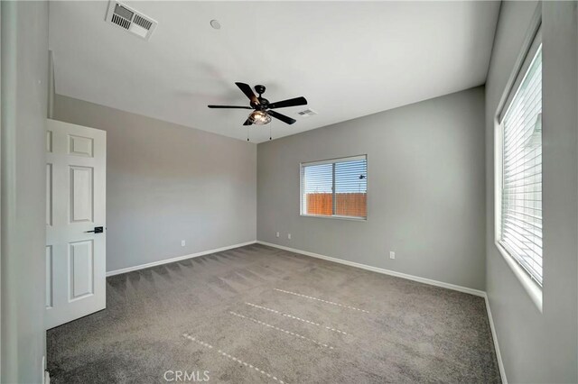 carpeted empty room with ceiling fan and plenty of natural light