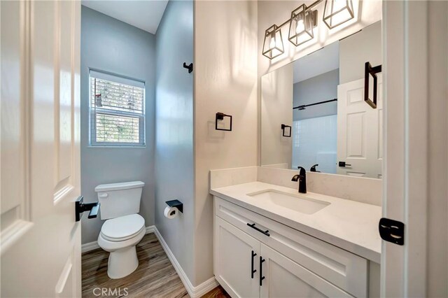 bathroom with wood-type flooring, vanity, walk in shower, and toilet