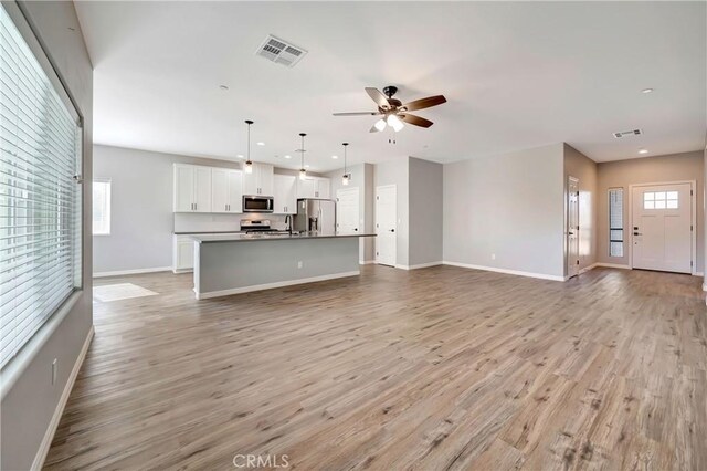 unfurnished living room with ceiling fan, light hardwood / wood-style floors, and a wealth of natural light