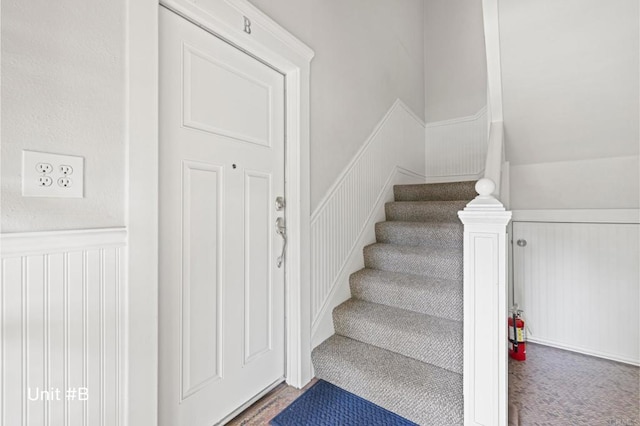 stairway featuring carpet floors and a wainscoted wall